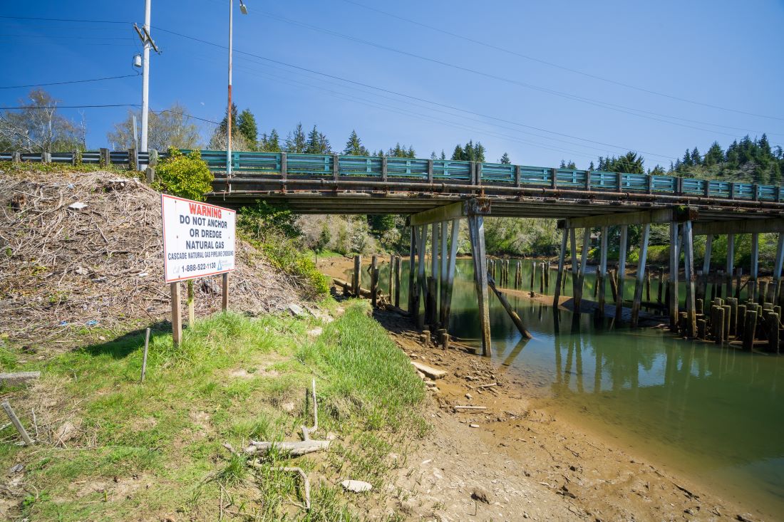 Vista del puente mirando hacia la orilla norte del río que muestra una señal de advertencia de una tubería de gas natural.