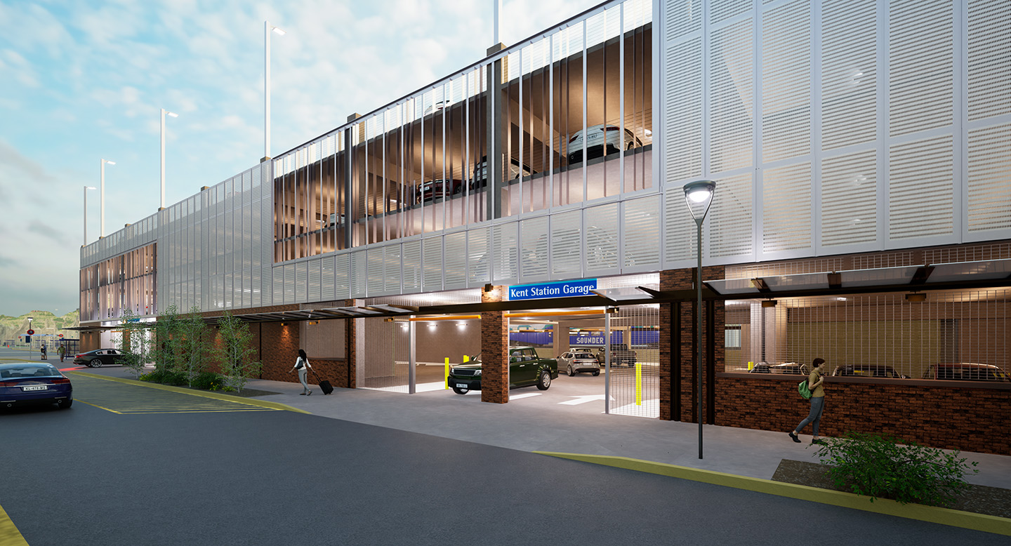 The image perspective is that of someone standing across Railroad Ave. from the parking garage. Two garage entrances can be seen with vehicles entering and leaving the garage. The garage is stone on the first level and metal on the levels above with vertical slats in some areas that offer a view into the garage. 